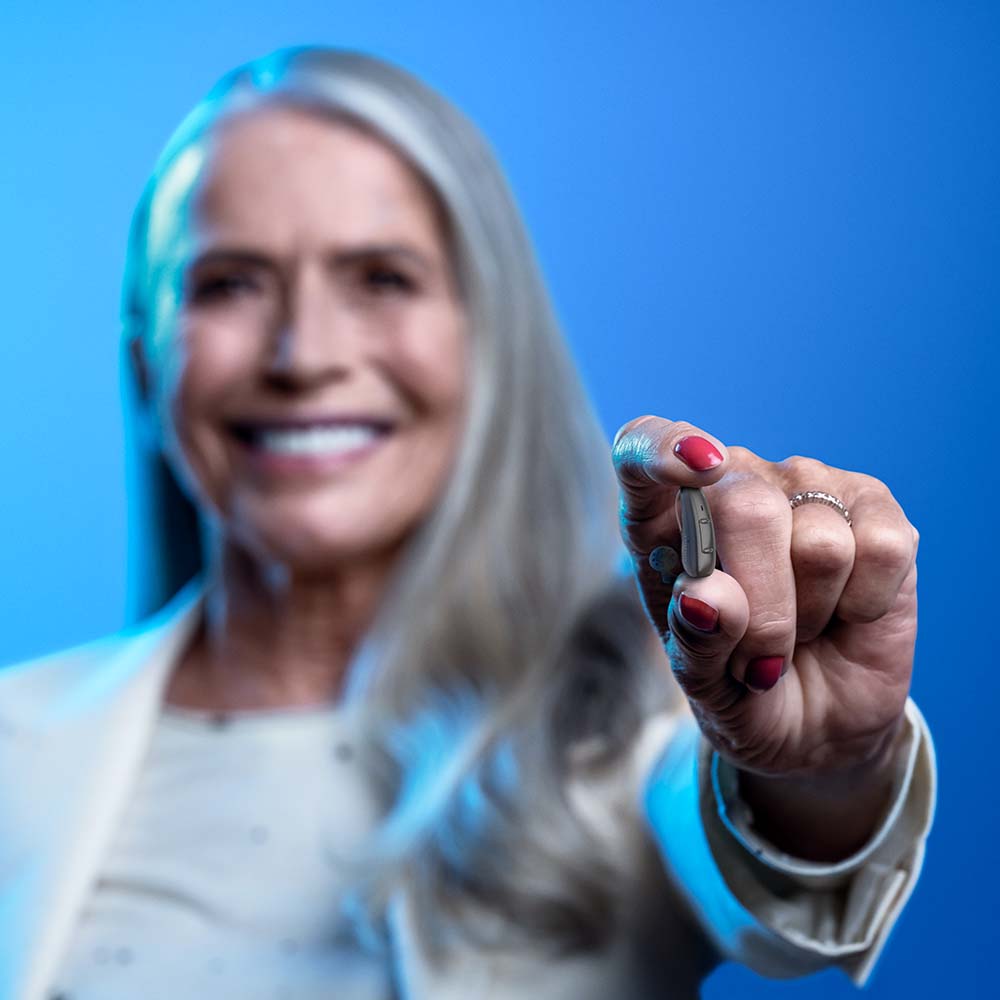Woman holding Pure Charge&Go AX hearing aid