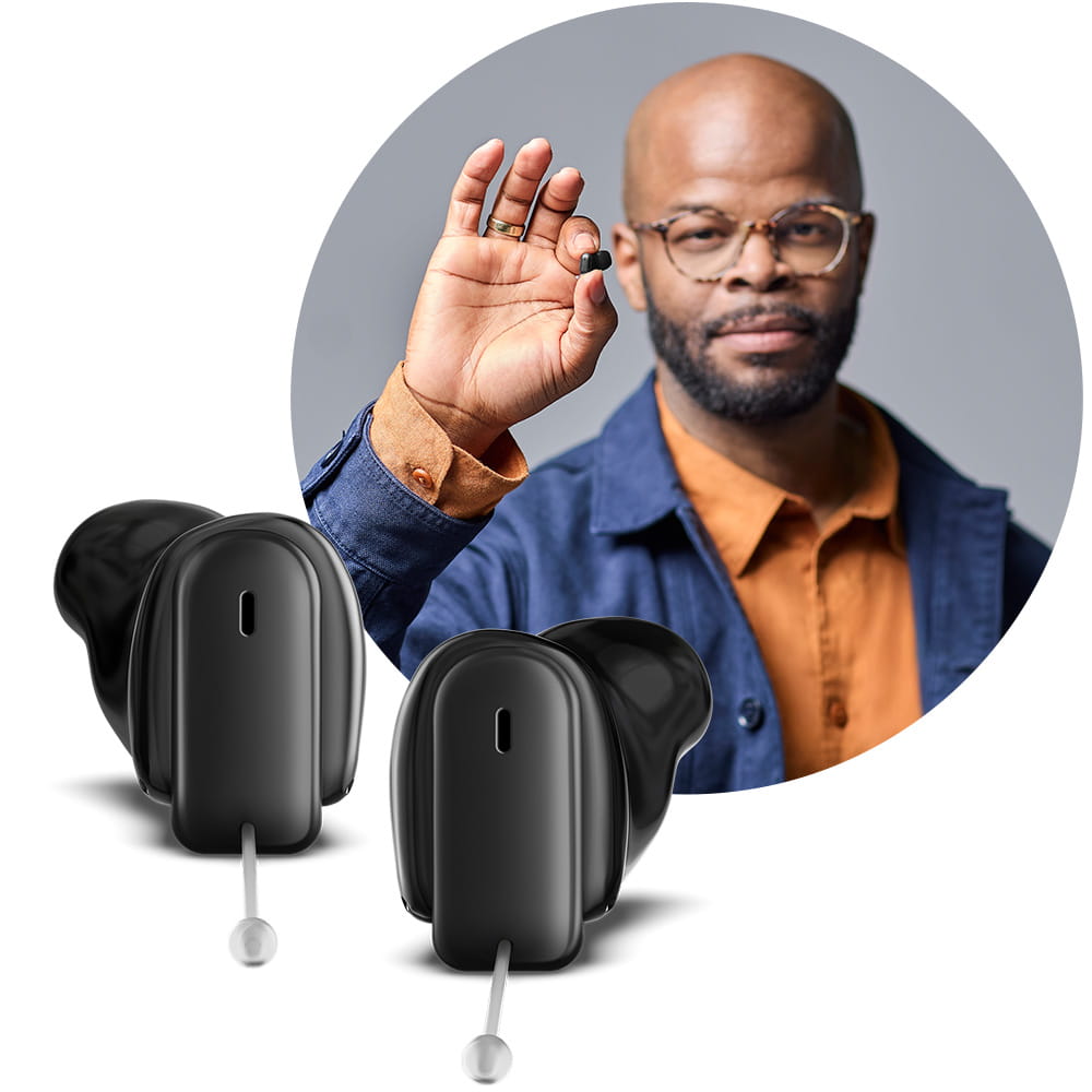 Man holding Insio Charge&Go CIC IX custom hearing aid between his fingers