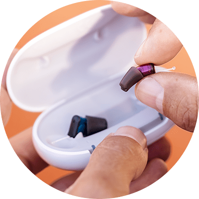 gros plan sur des mains qui sortent de leur chargeur un silk charge and go ix de signia, la première aide auditive invisible et sans pile