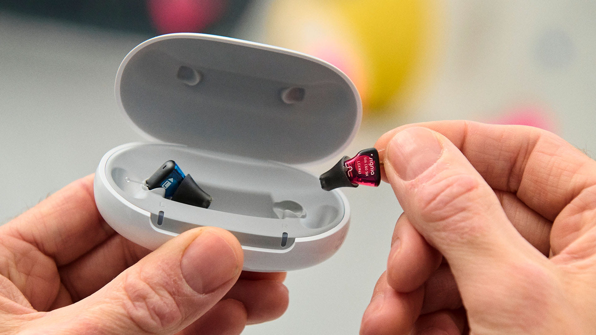 Signia hearing aid being held — small enough to fit in your palm