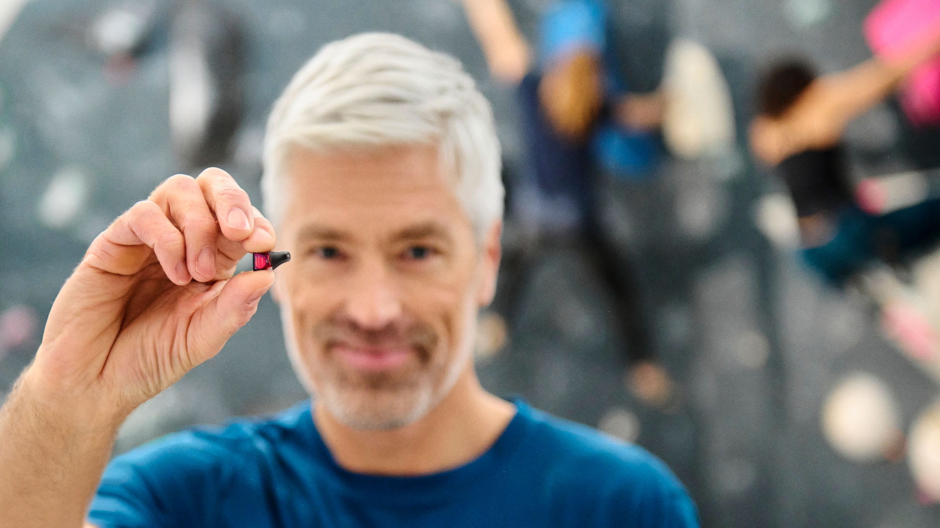 Man in bouldering hall holding Silk Charge&Go IX hearing aid