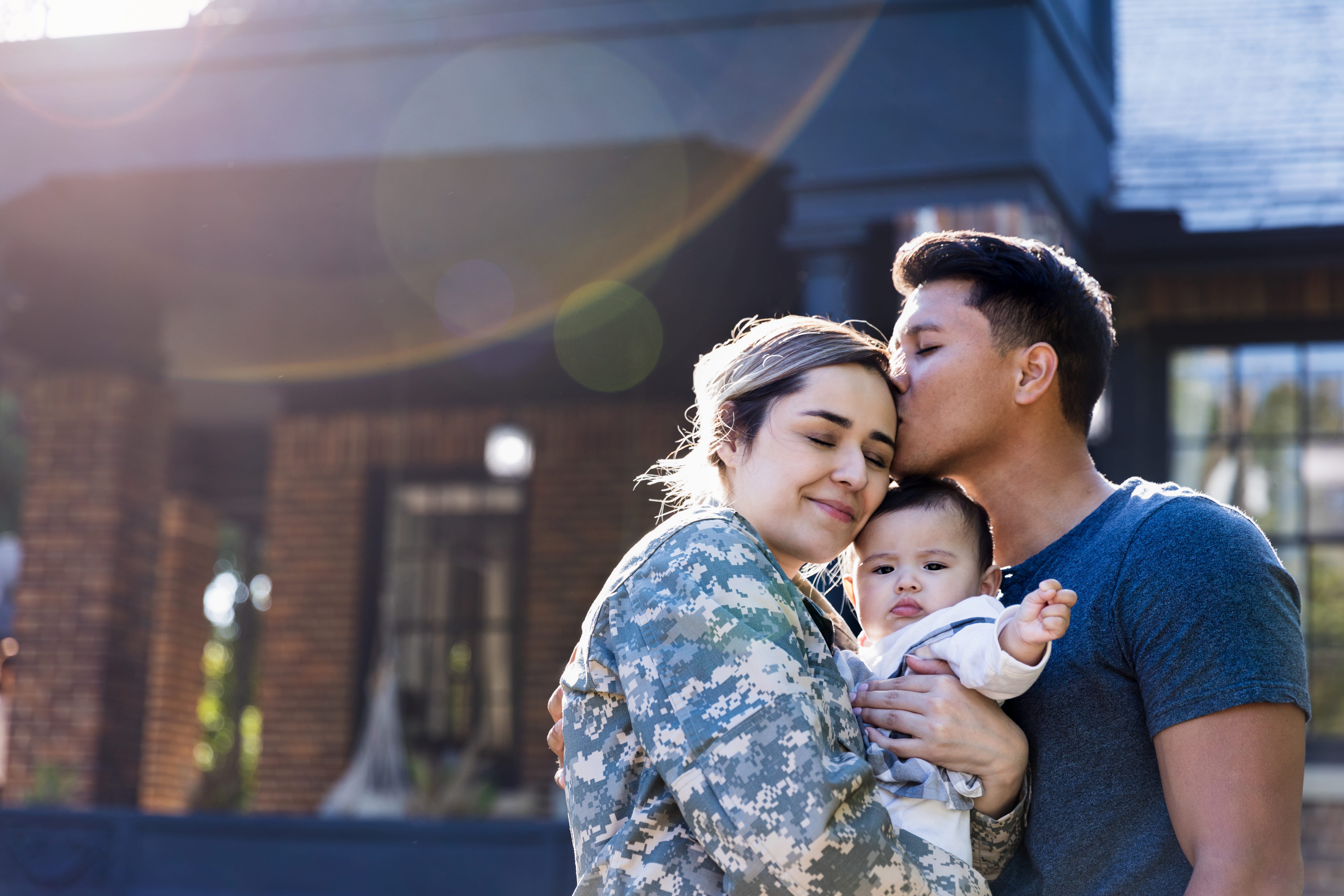 woman soldier hugging husband and small child